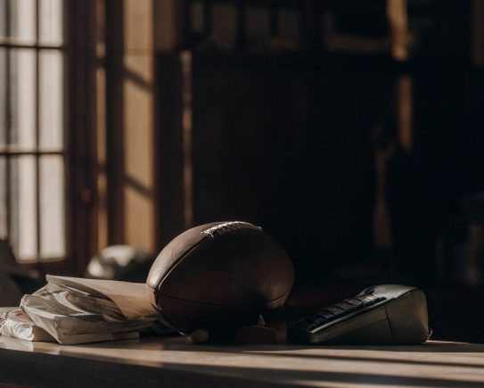 Reçus et notes de frais posés sur un bureau avec un ballon de sport et une calculatrice, symbolisant la gestion financière des associations sportives.
