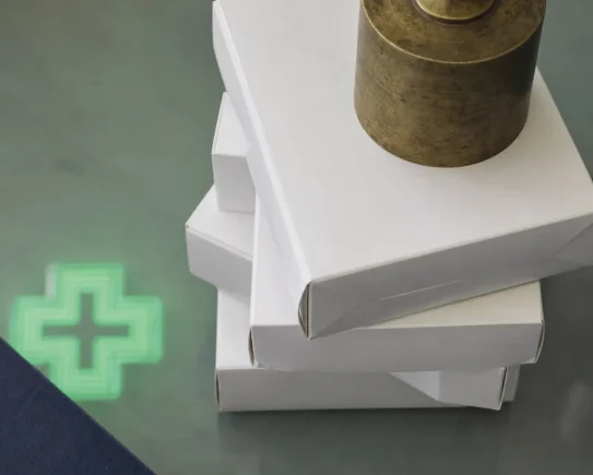 Boîtes de médicaments génériques maintenues par un presse-papier, symbole des plafonds de remises génériques gravés dans la loi