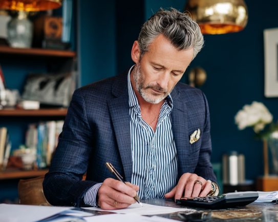 Homme calculant sa CDHR sur des documents fiscaux avec accents turquoise et bleu foncé.